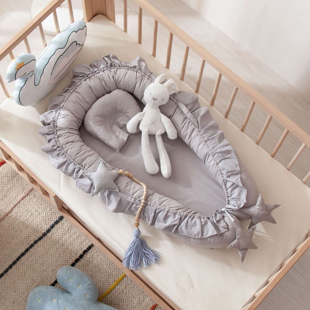 Gray crib bumper with star decorations in a crib with toys