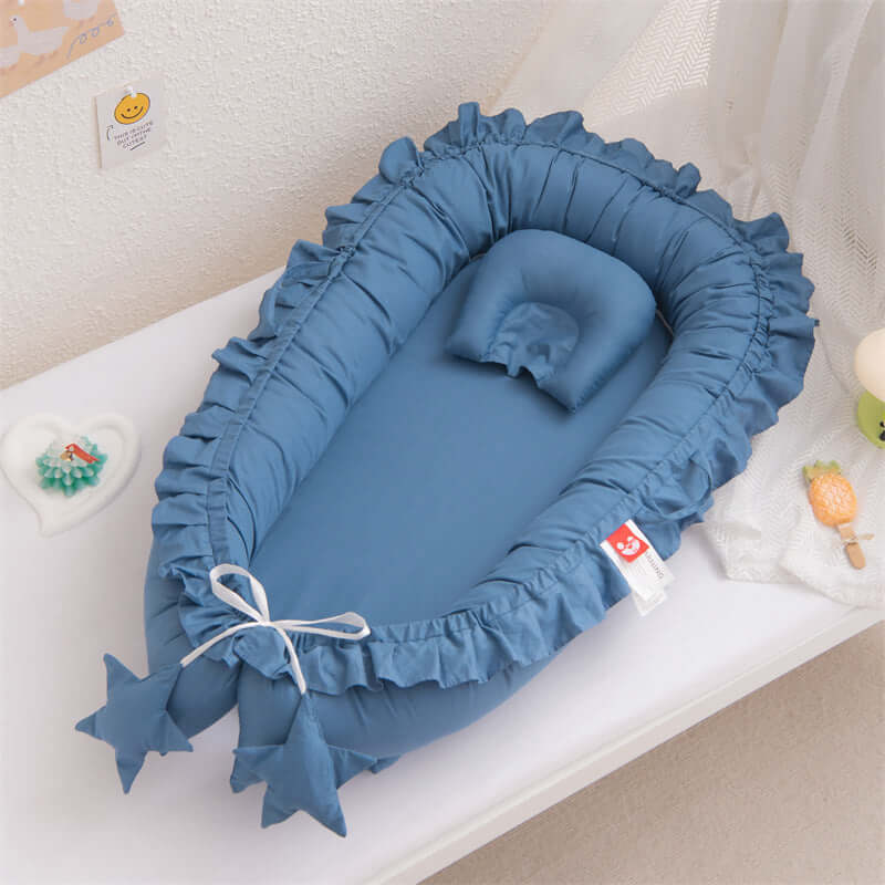 Blue baby crib with ruffled edges on a white surface