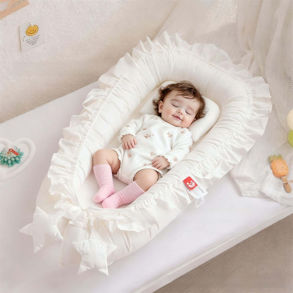 Baby sleeping in a white crib with ruffled edges, wearing a white outfit and pink socks.